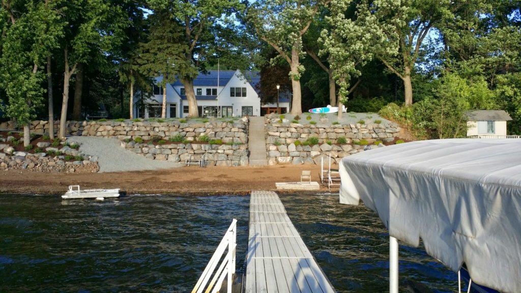 Two large tiers of fieldstone boulder walls  retain the slope on this lakefront property.