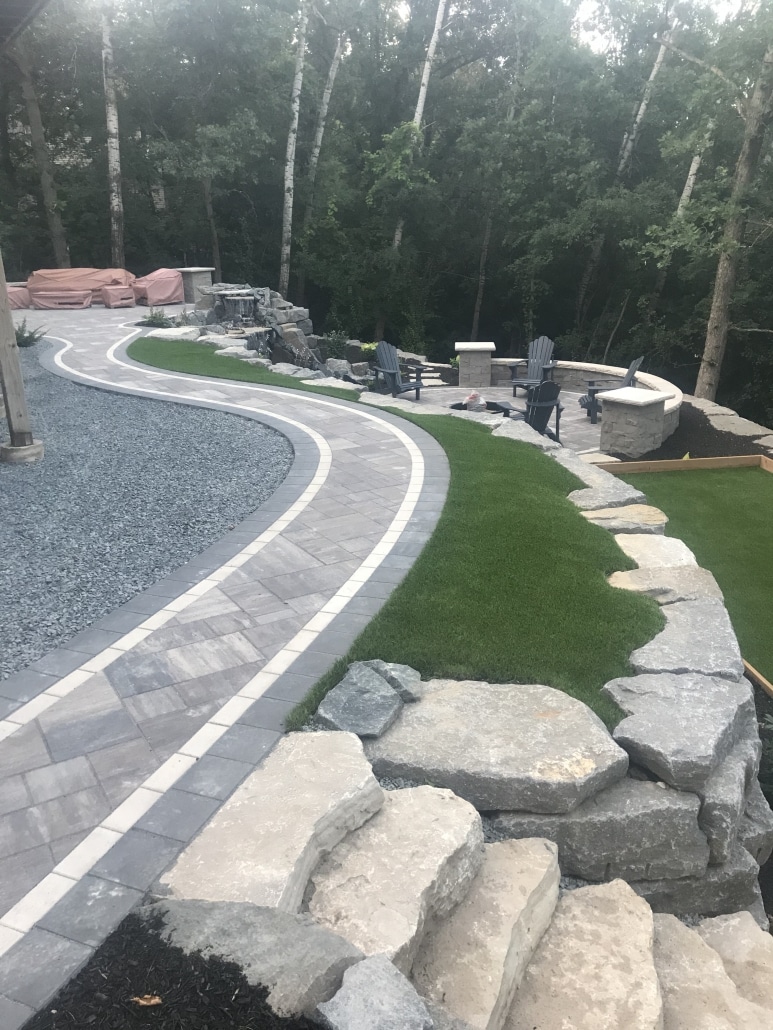 A long boulder wall near the house creates a level area for this clients patio and bocce court.