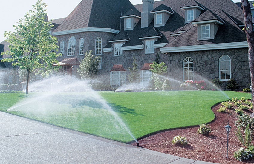 Residential sprinkler system watering lawn and landscape beds
