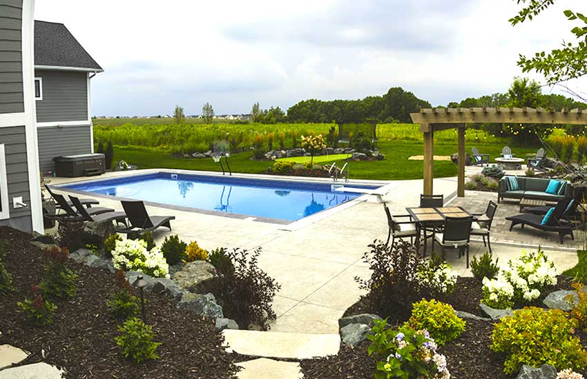 Inground pool with granite patio pavers, cedar pergola, outdoor dining set, and lounge chairs in Plymouth, MN